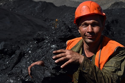 Loading machine operator with a piece of coal at the Nerungrinsk Open Pit, Yakutugol